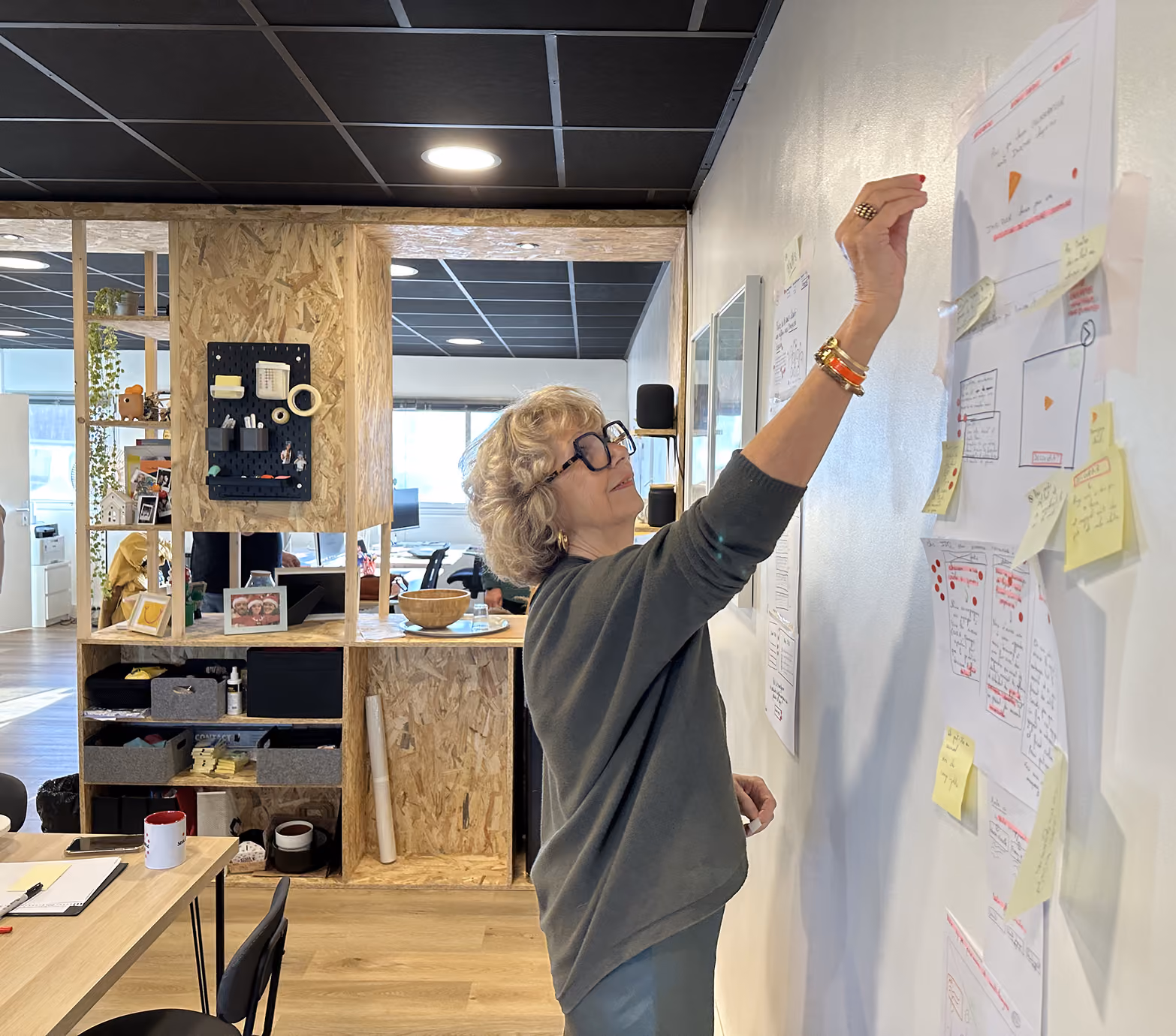 Une participante accroche des maquettes et des post-it sur un mur