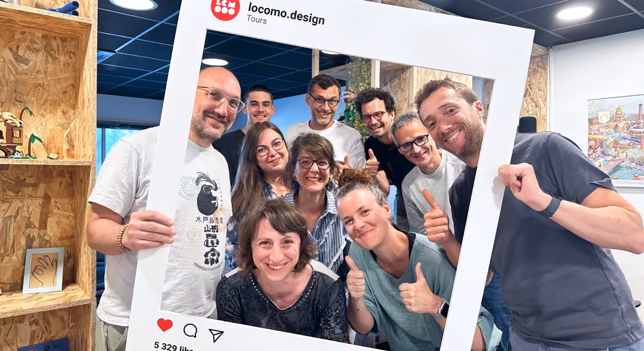 Groupe souriant derrière un cadre Instagram « locomo.design »