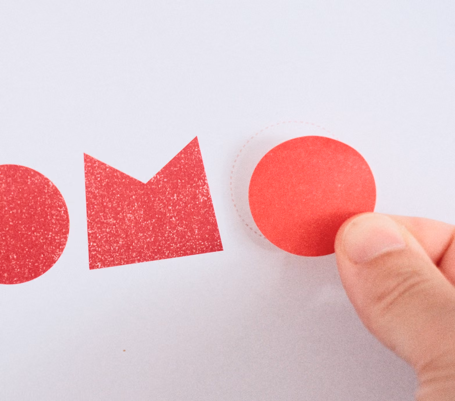 Main collant une forme rouge pour composer le logo Locomo