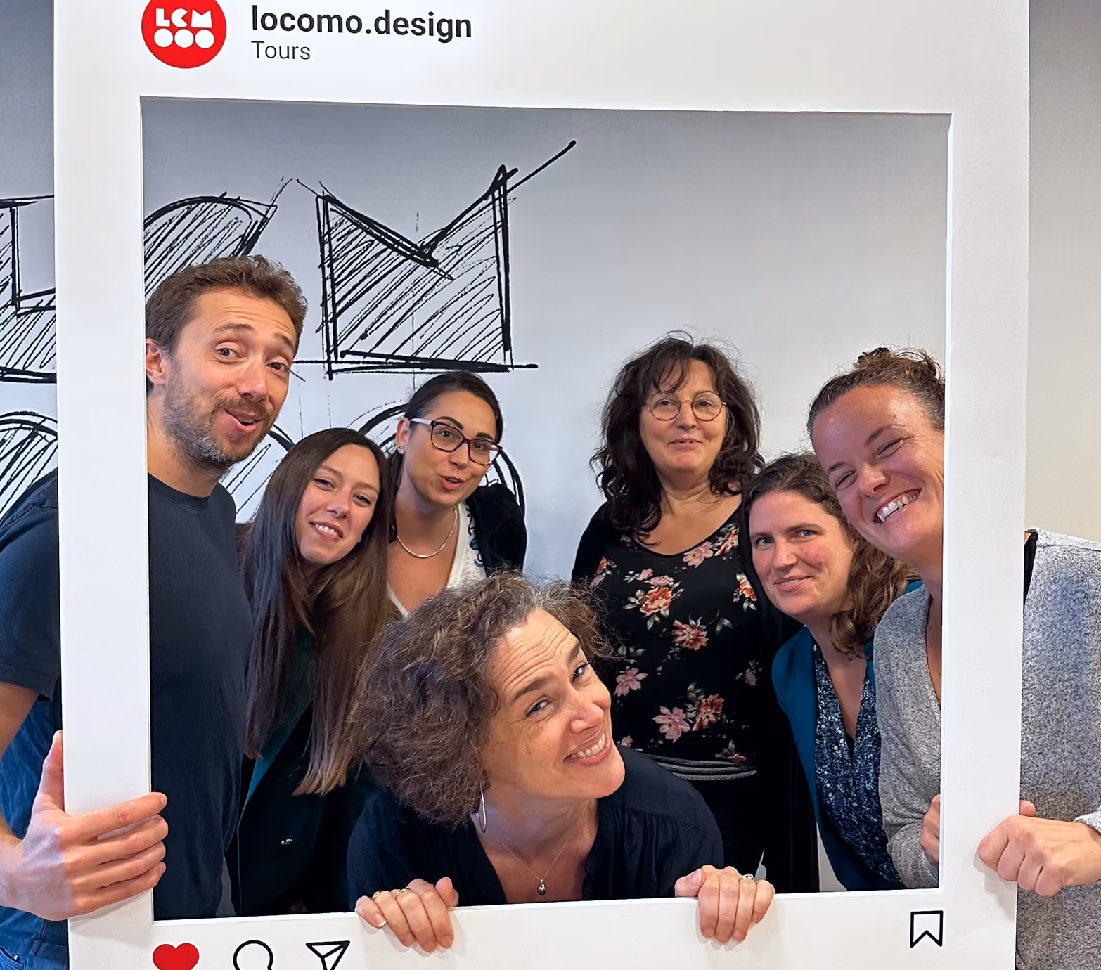 Groupe souriant derrière un cadre Instagram « locomo.design »