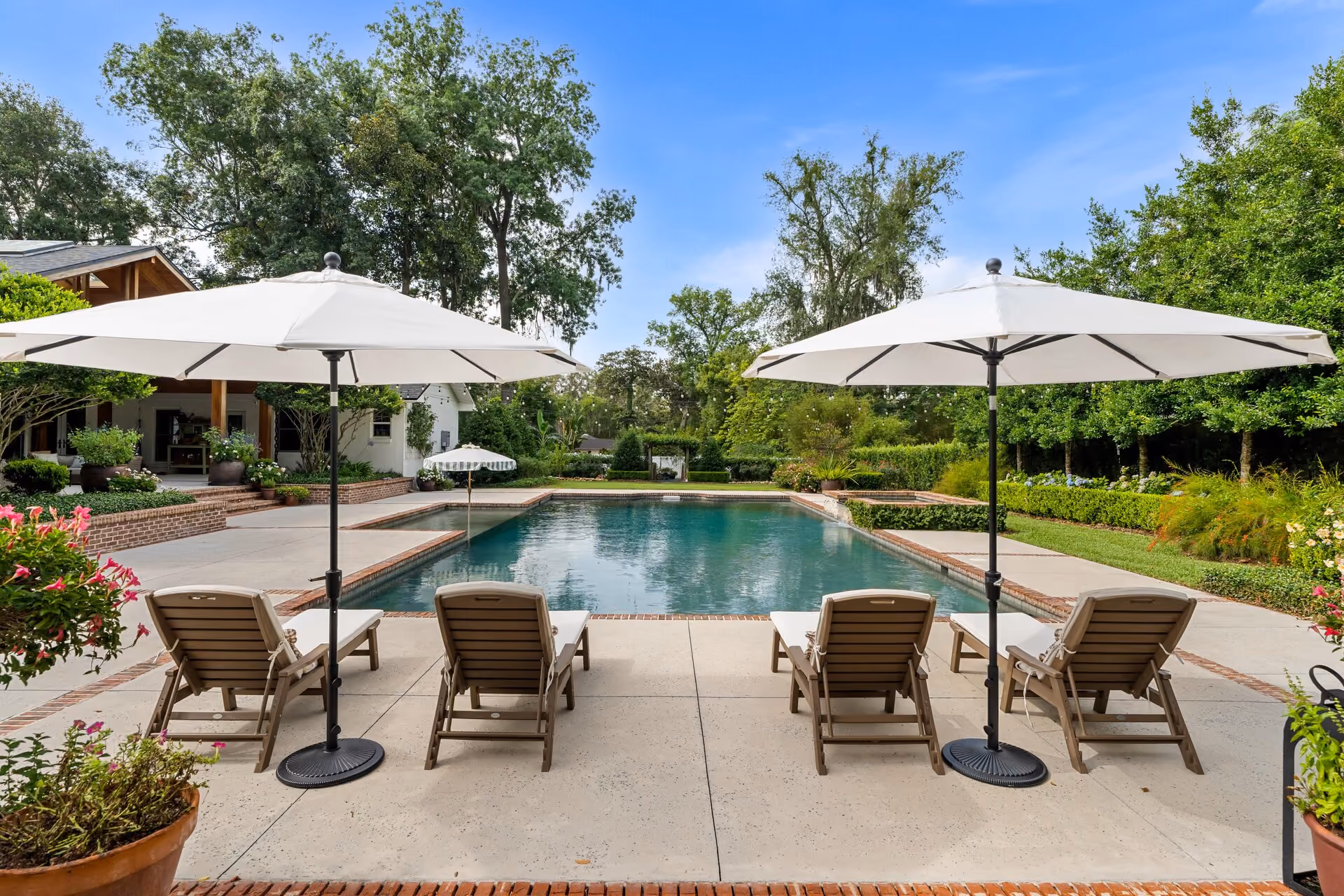 Backyard swimming pool with patio umbrellas and loungers
