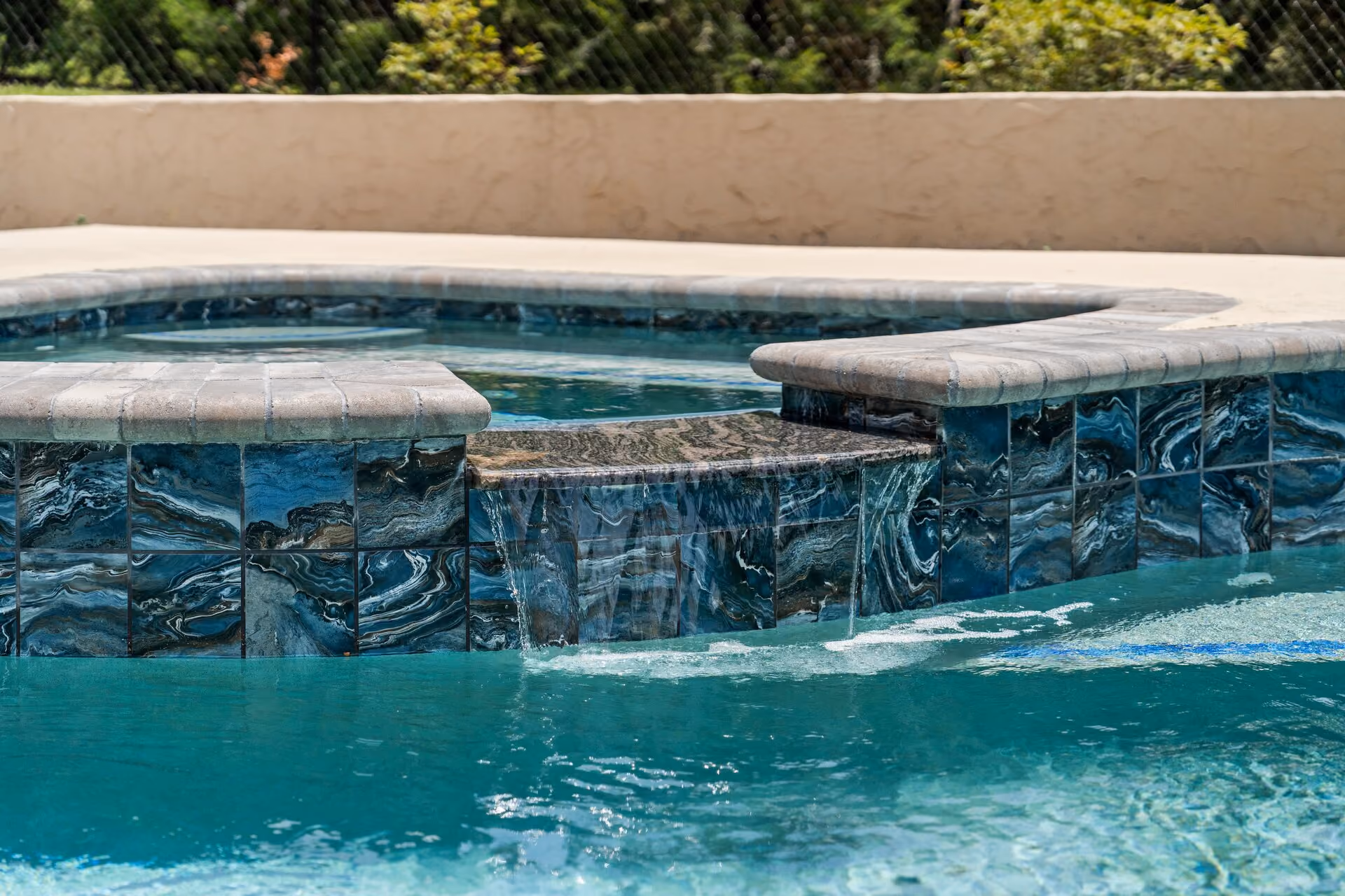 Raised spa spilling over into a swimming pool