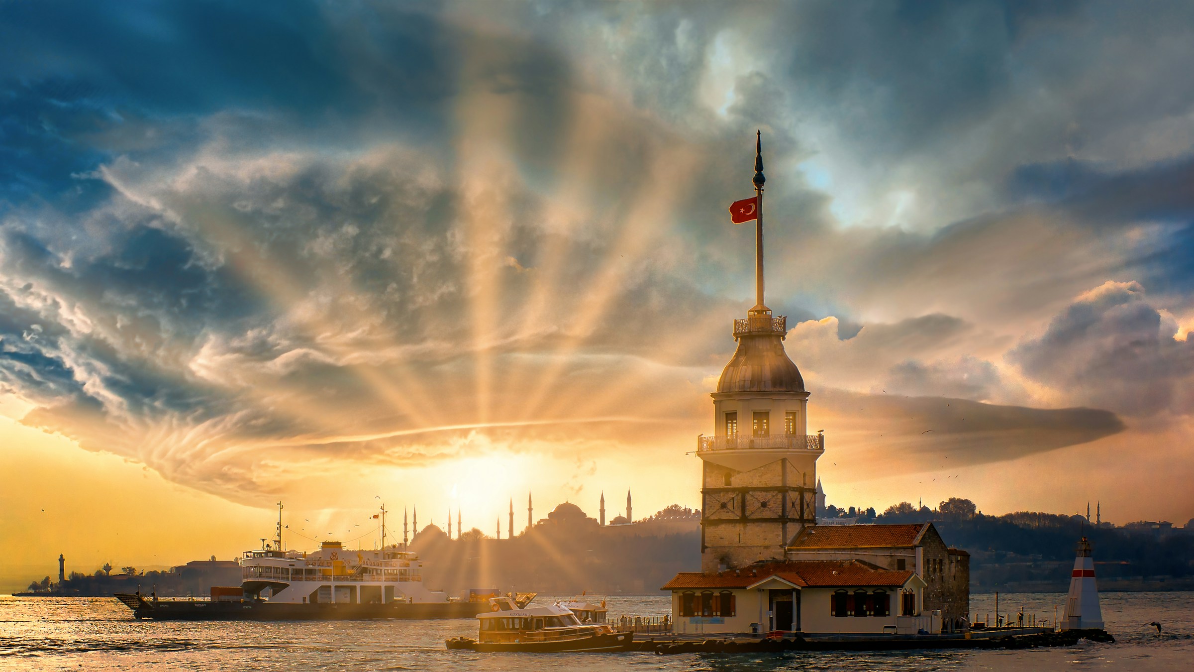 The Maiden's Tower on the Bosphorus at sunset, with a ferry and the Istanbul skyline behind