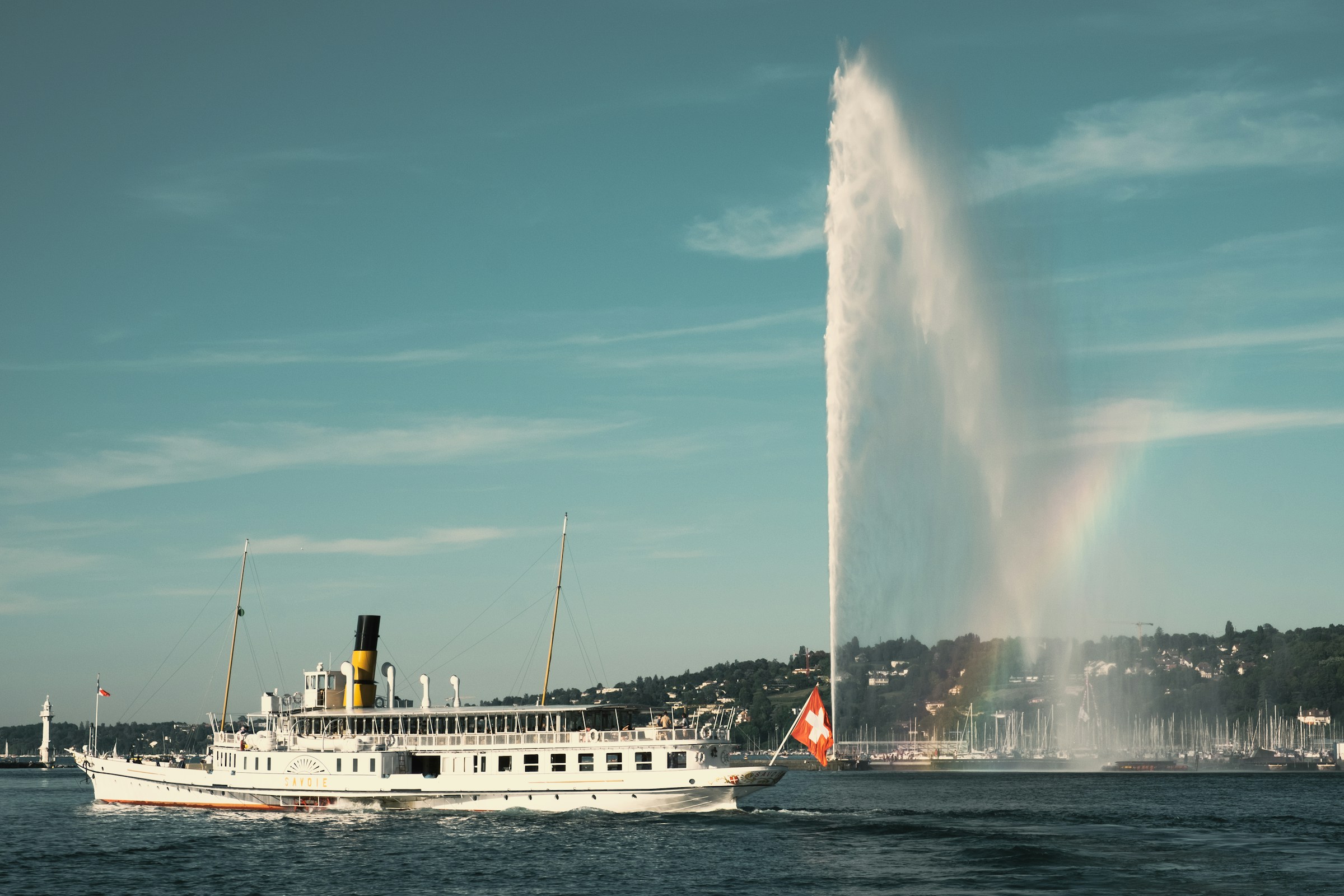 A passenger vessel on Lake Geneva with the Jet d'Eau fountain behind it
