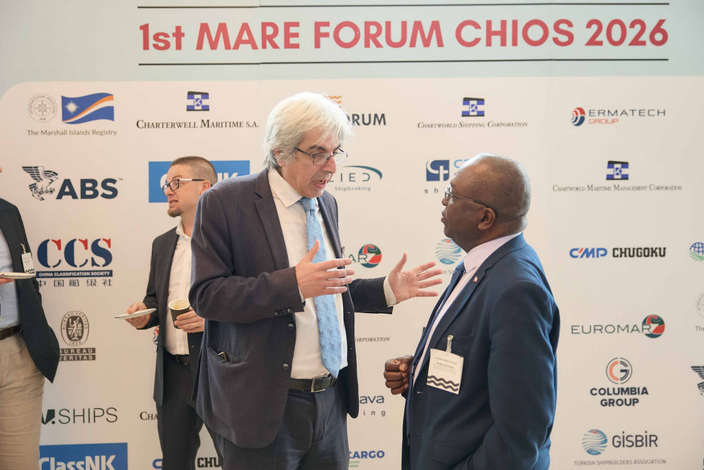 Two delegates in conversation at the Mare Forum backdrop, Chios 2026