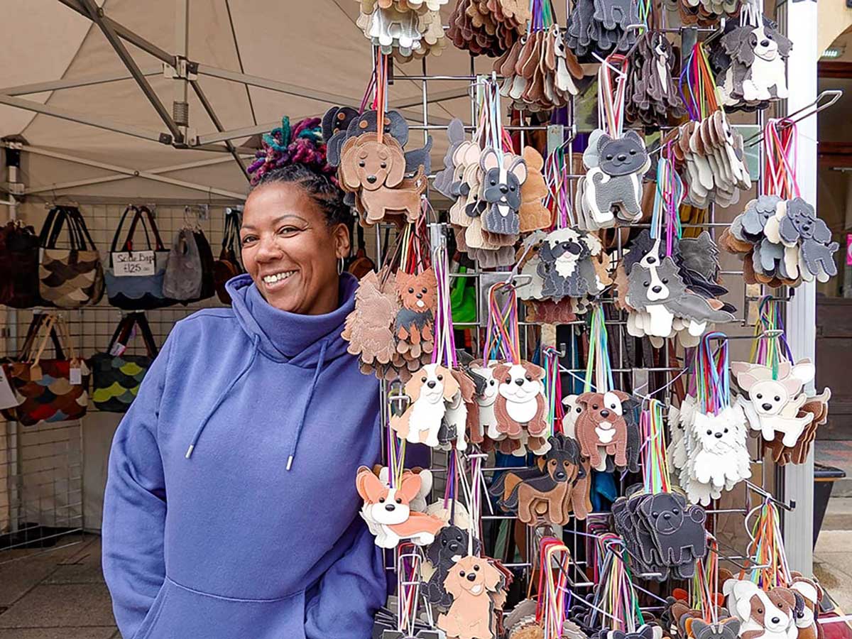 A market stall holder standing in front of their work and stall on the market.