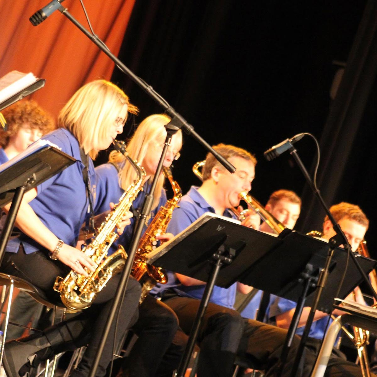 A cropped photograph of members of the Terry Hill Big Band playing brass instruments