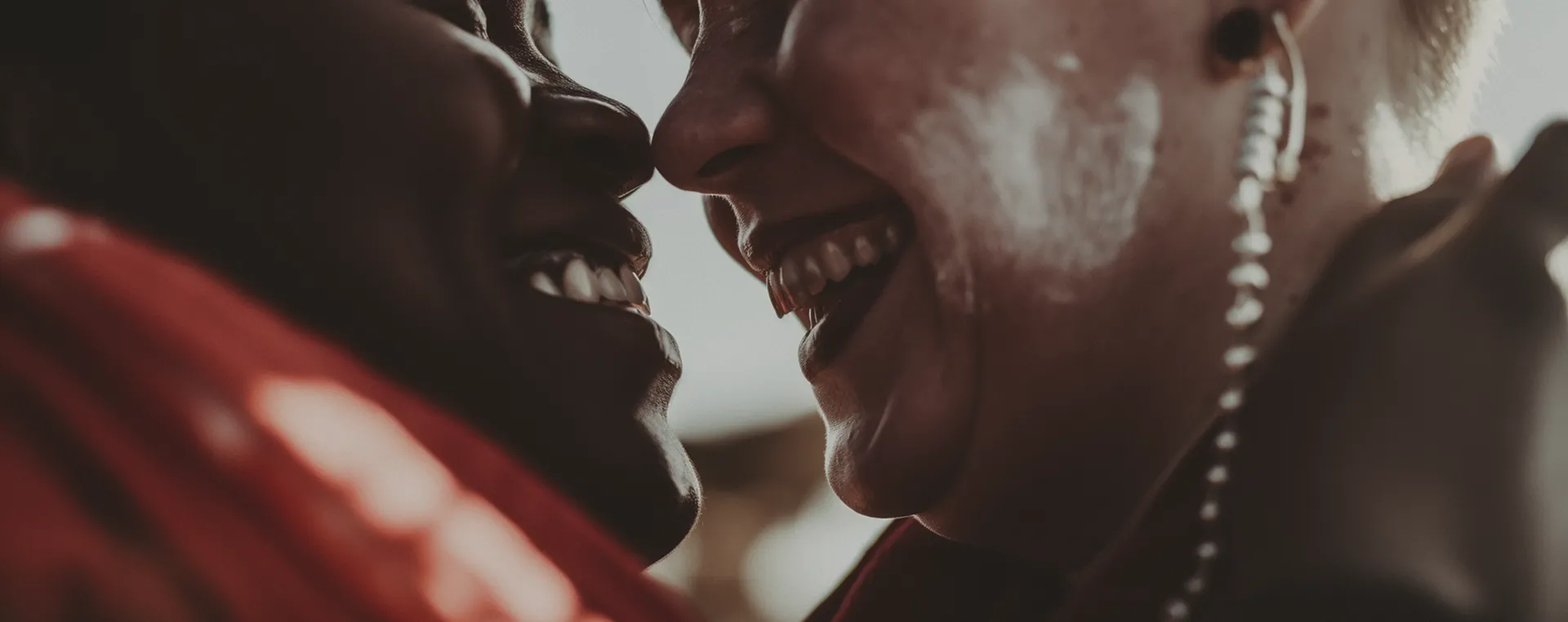 Close-up of two people smiling closely facing each other, showing joy and intimacy.
