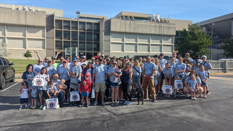 IBEW 453 members and their families posing for a group photo outside a stadium before a parade