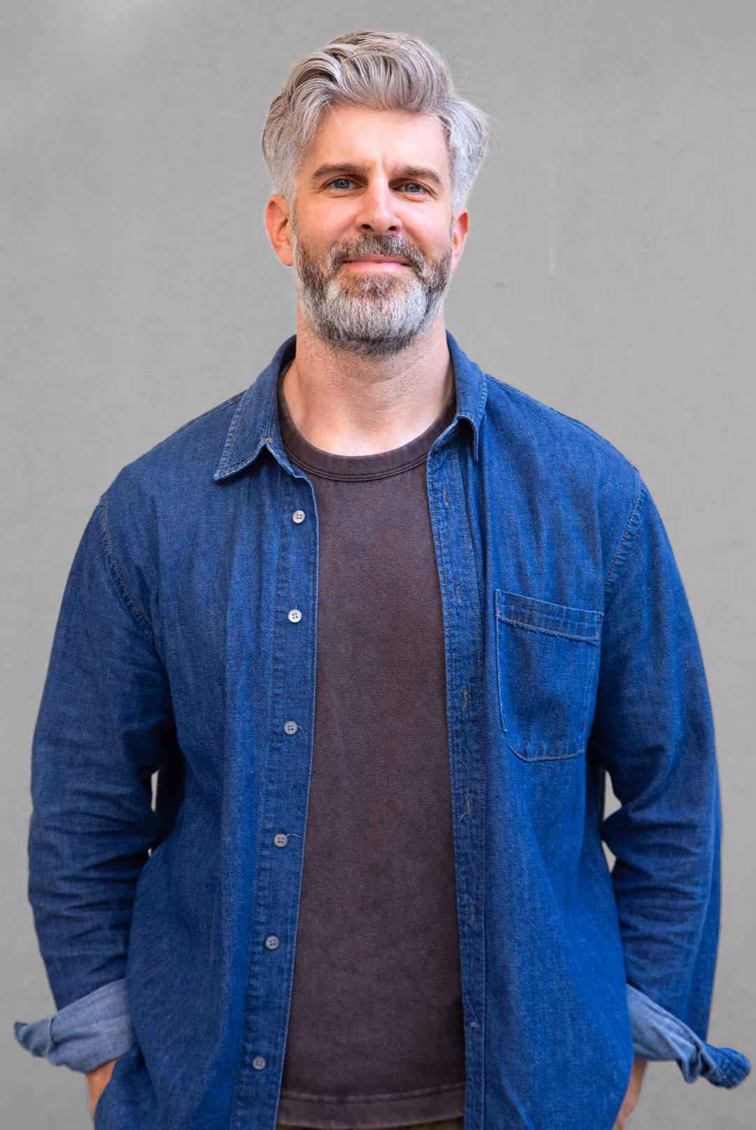 Smiling middle-aged man with gray hair and beard wearing a corduroy shirt over a t-shirt.