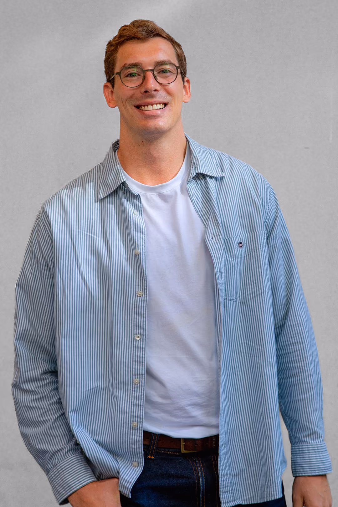 Smiling man with short hair wearing a white button-up shirt against a light background.