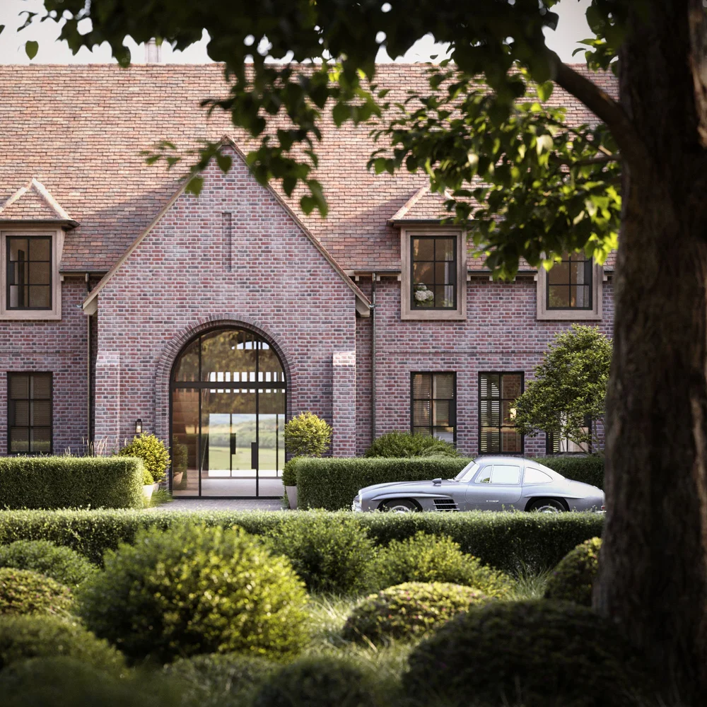 Classic silver car parked in front of a brick house with arched glass doors and trimmed hedges.