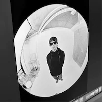 Person wearing sunglasses standing in a circular, monochrome fisheye perspective.