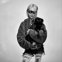 Stylish individual in oversized sweater holding a small black dog.
