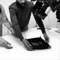 Two people collaborating at a table with photography equipment overhead.