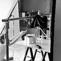 A black and white behind-the-scenes photo of e-commerce photography at LRP studios, showing a person arranging products under an overhead camera rig.