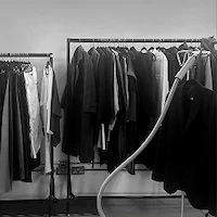 A black and white photo of the wardrobe styling area during e-commerce photography at LRP studios, showing clothing racks filled with garments and a steamer.