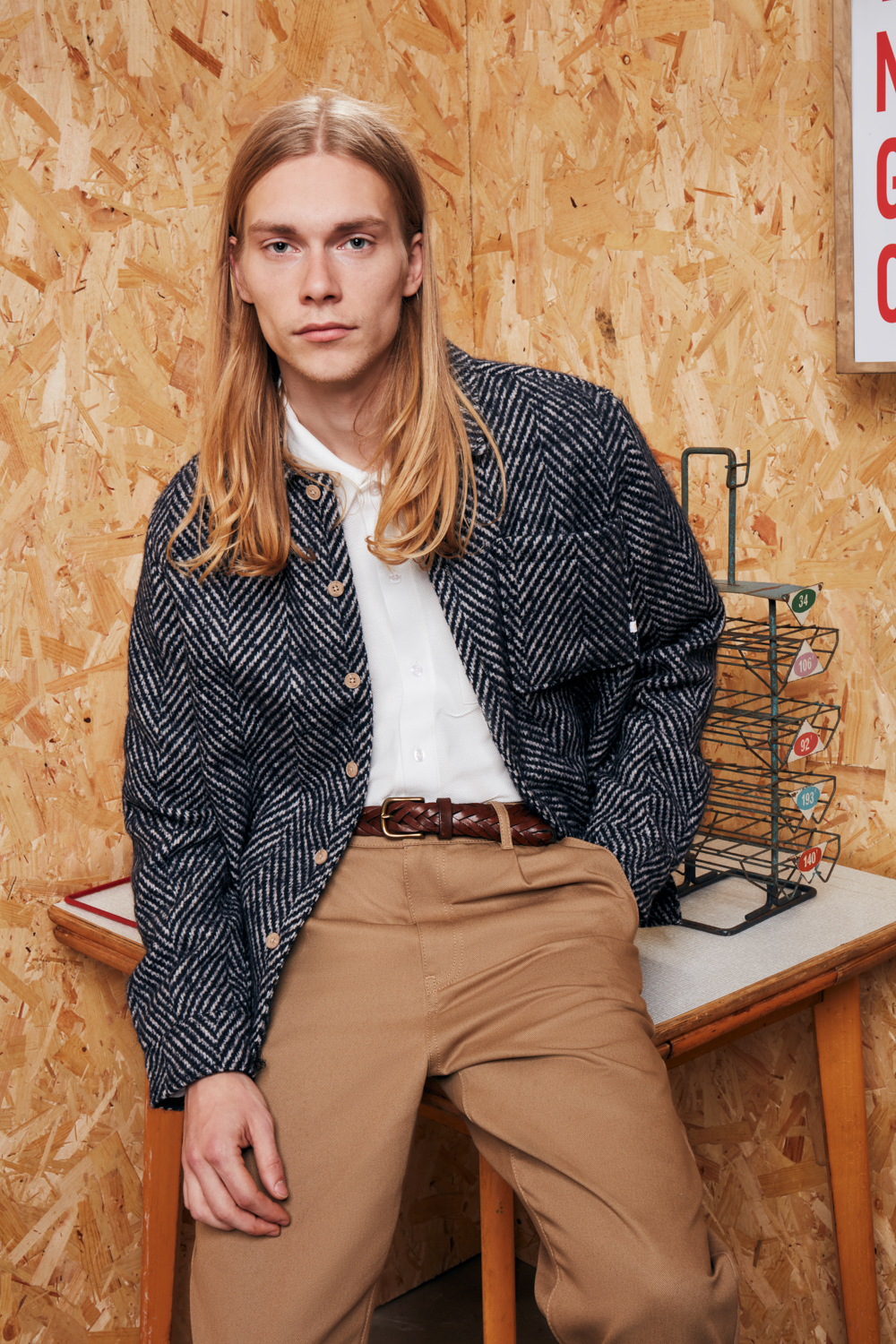 Male model leaning on the table in beige trousers and dark trousers. creative eCommerce fashion shoot for Farah brand