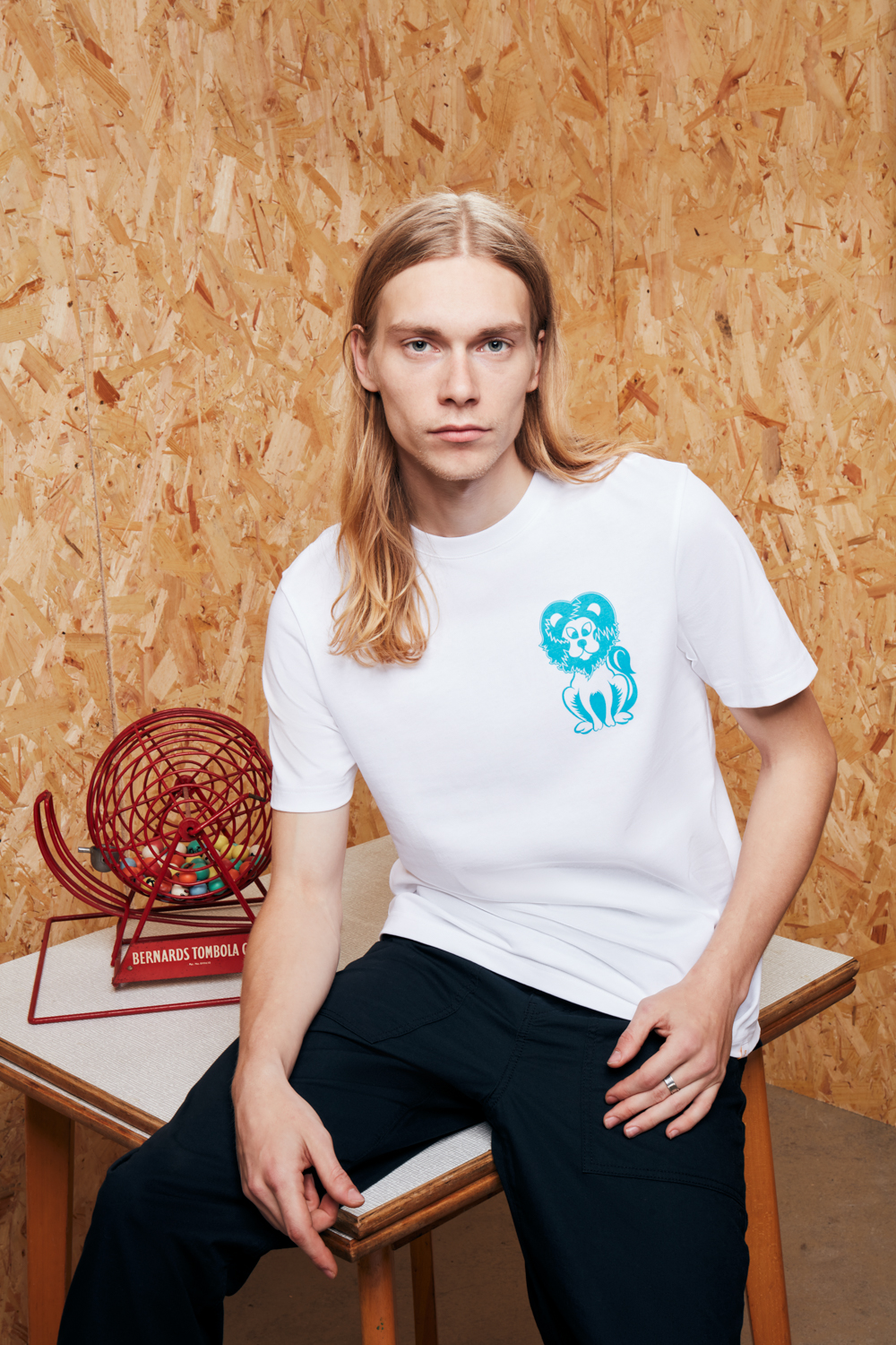 male model leaning on the table with white t-shirt and dark trousers shot for Farah creative fashion shoot