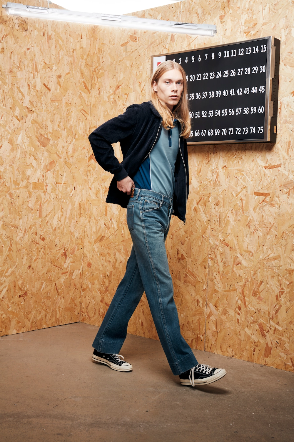Male model posing in a creative setting surrounded by Bingo boards and MDF with a light on an angle. shot for Farah Menswear