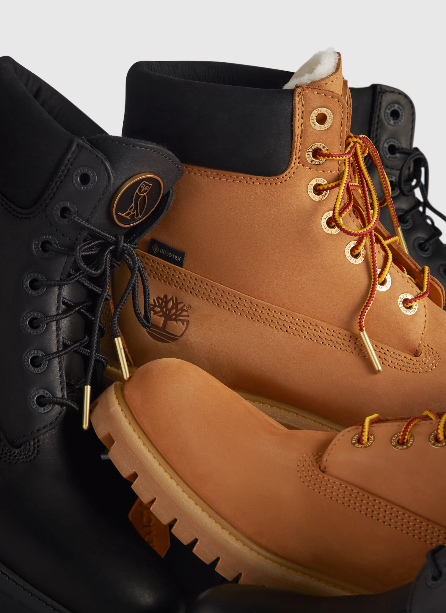 Close-up product photography detailing the gold OVO owl logo badge, embossed Timberland tree logo, shearling lining, and premium laces with gold aglets.