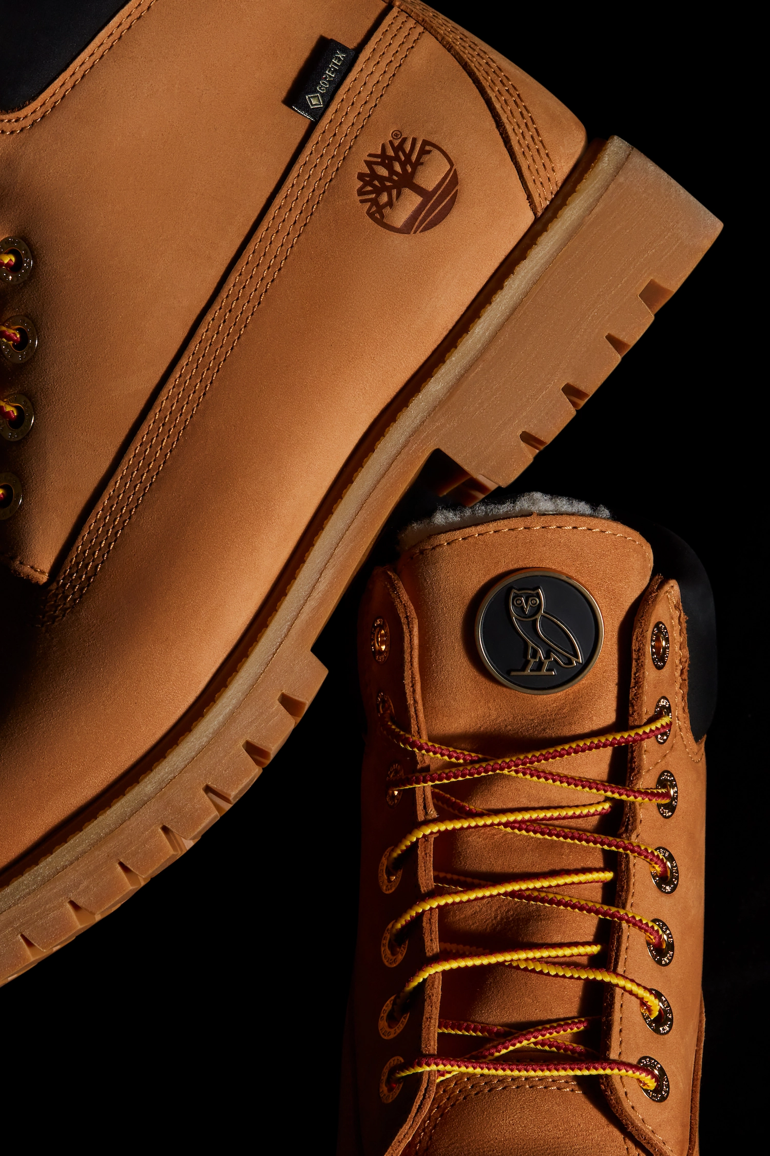 Detailed macro product shot highlighting the tongue with the gold OVO owl logo badge, classic red and yellow laces, gold eyelets, and the embossed Timberland tree logo on the side.