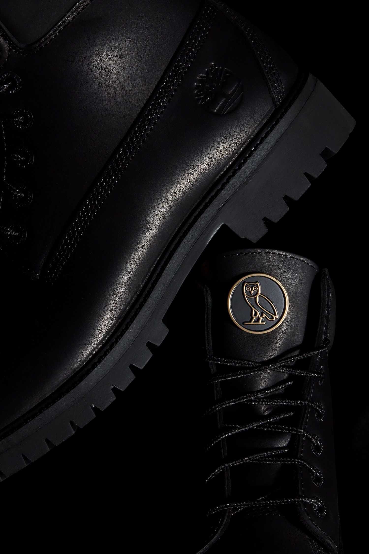 OVO x Timberland collaboration black leather boots. Detailed dark product photography showcasing the thick lug sole, embossed Timberland tree logo, tonal laces, and signature gold OVO owl logo badge