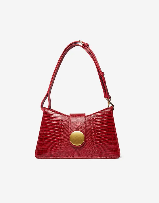 Red textured handbag with an adjustable strap and a large round gold clasp on front.