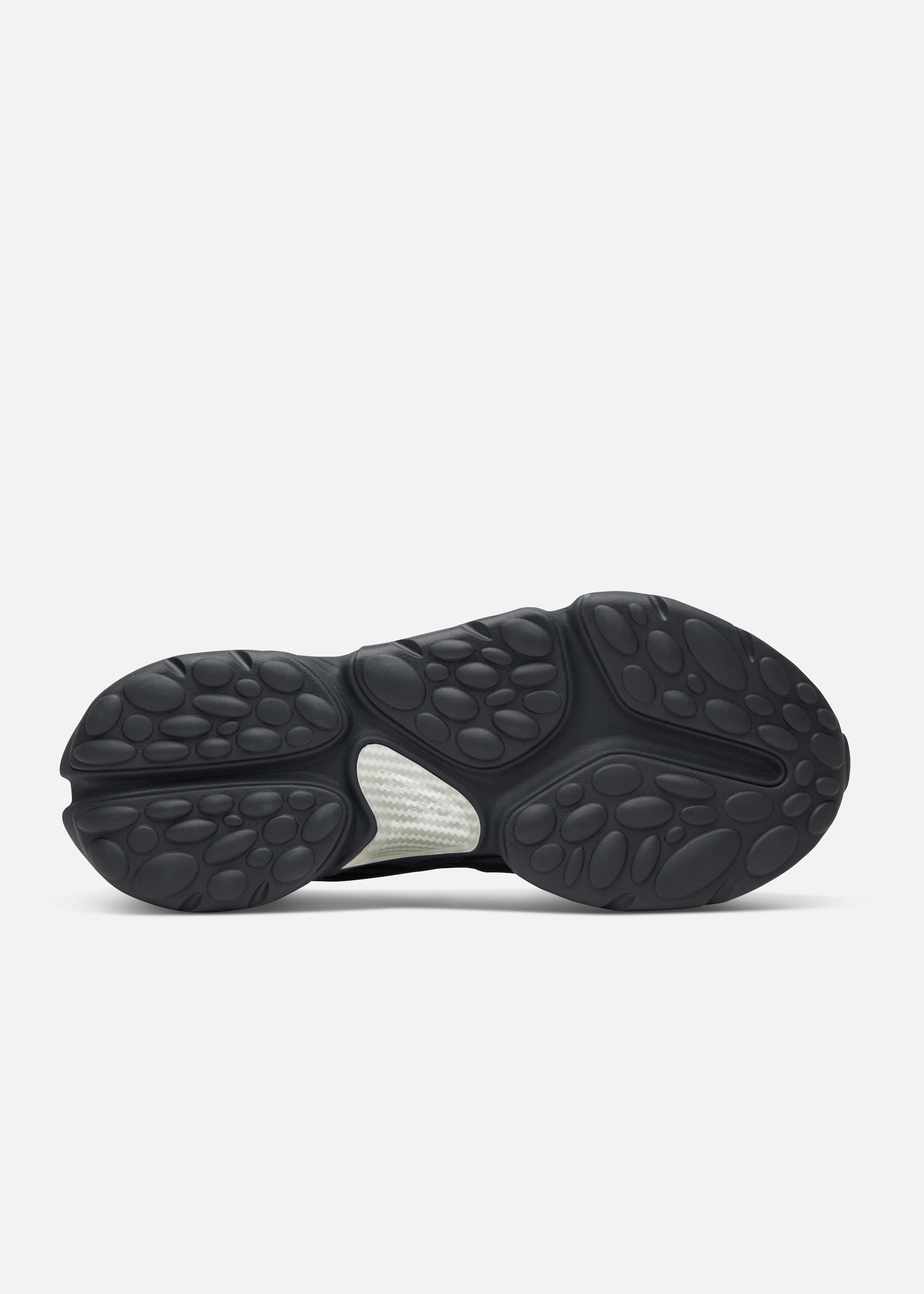 Black rubber Axel Arigato sole of a sneaker with rounded textured pods and a white central patch.