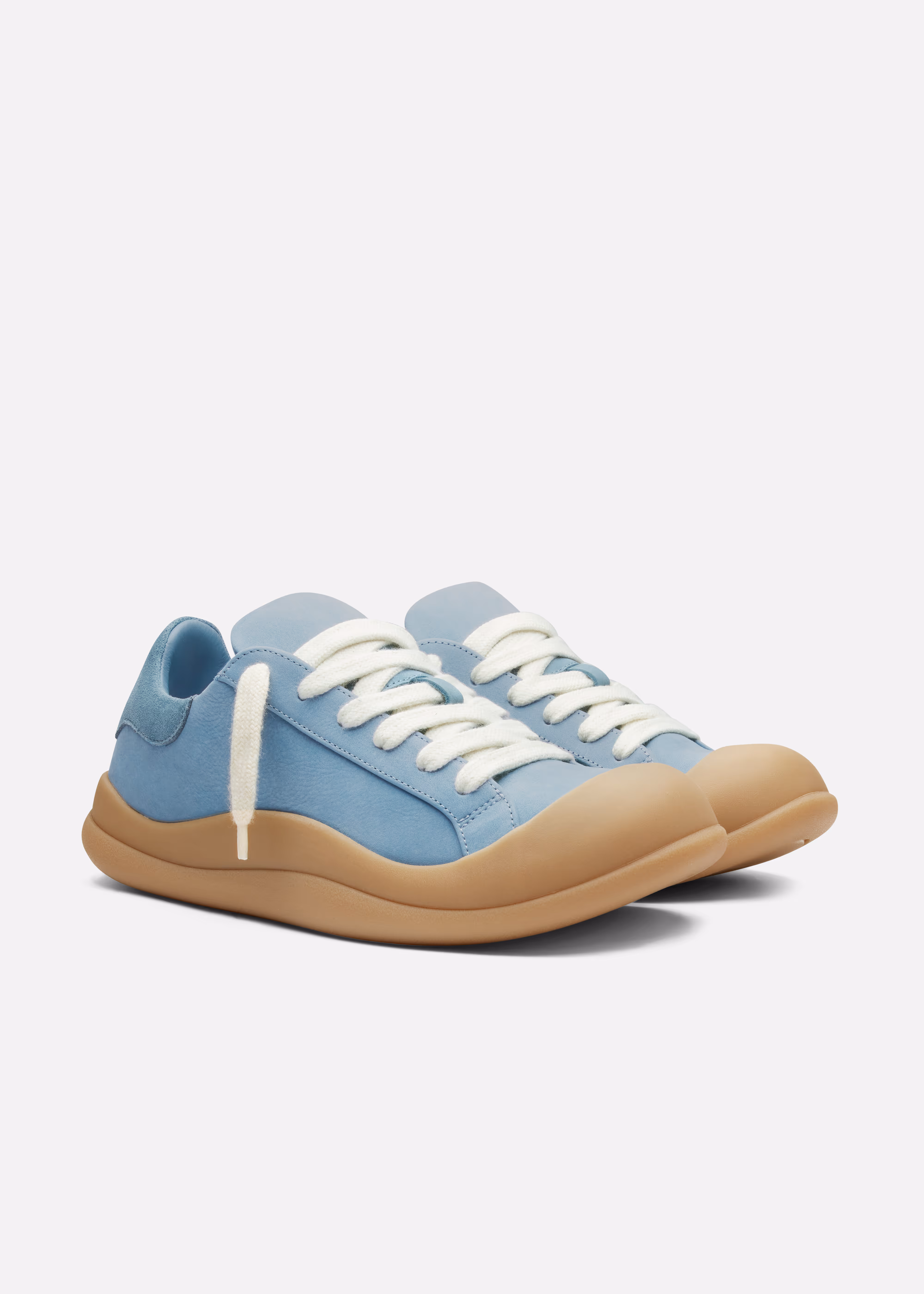Pair of light blue Axel Arigato  sneakers with white laces and tan rubber soles on a white background.