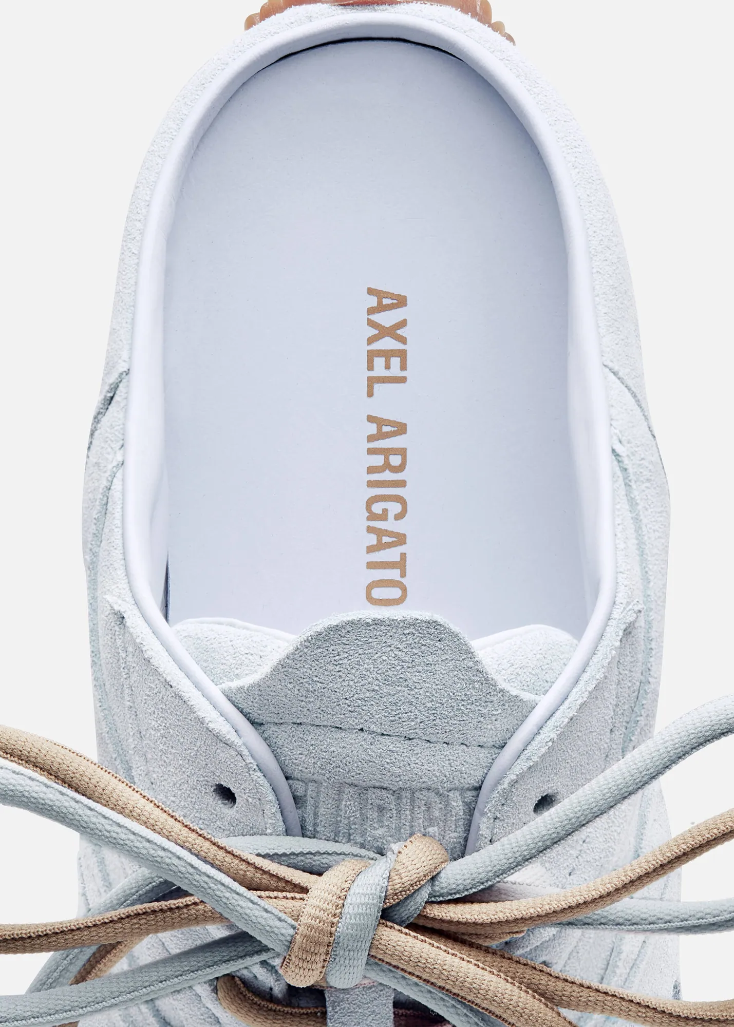 Top close-up of a light gray suede sneaker with beige and gray laces and Axel Arigato brand insole.