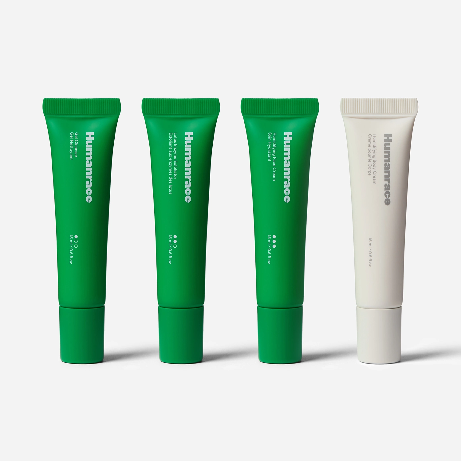 Four Humanrace skincare tubes in a row, three green and one white on a white background.