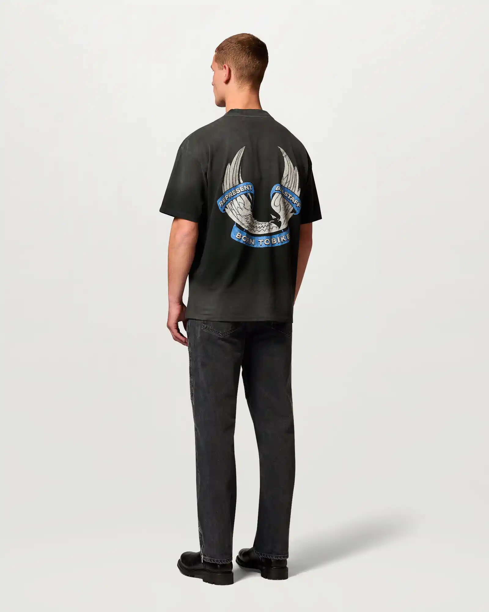 Man wearing black Belstaff t-shirt with winged eagle and blue ribbon graphic on back reading Born to Bike.