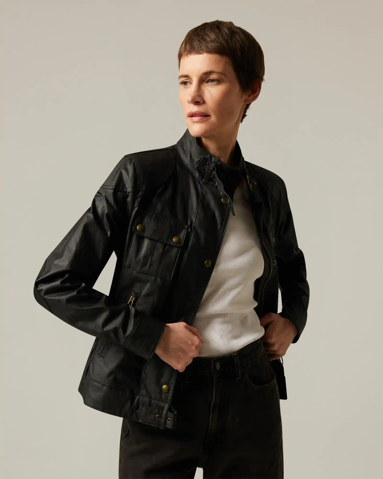 Woman wearing a black Belstaff leather jacket and white top, posing against a plain background.