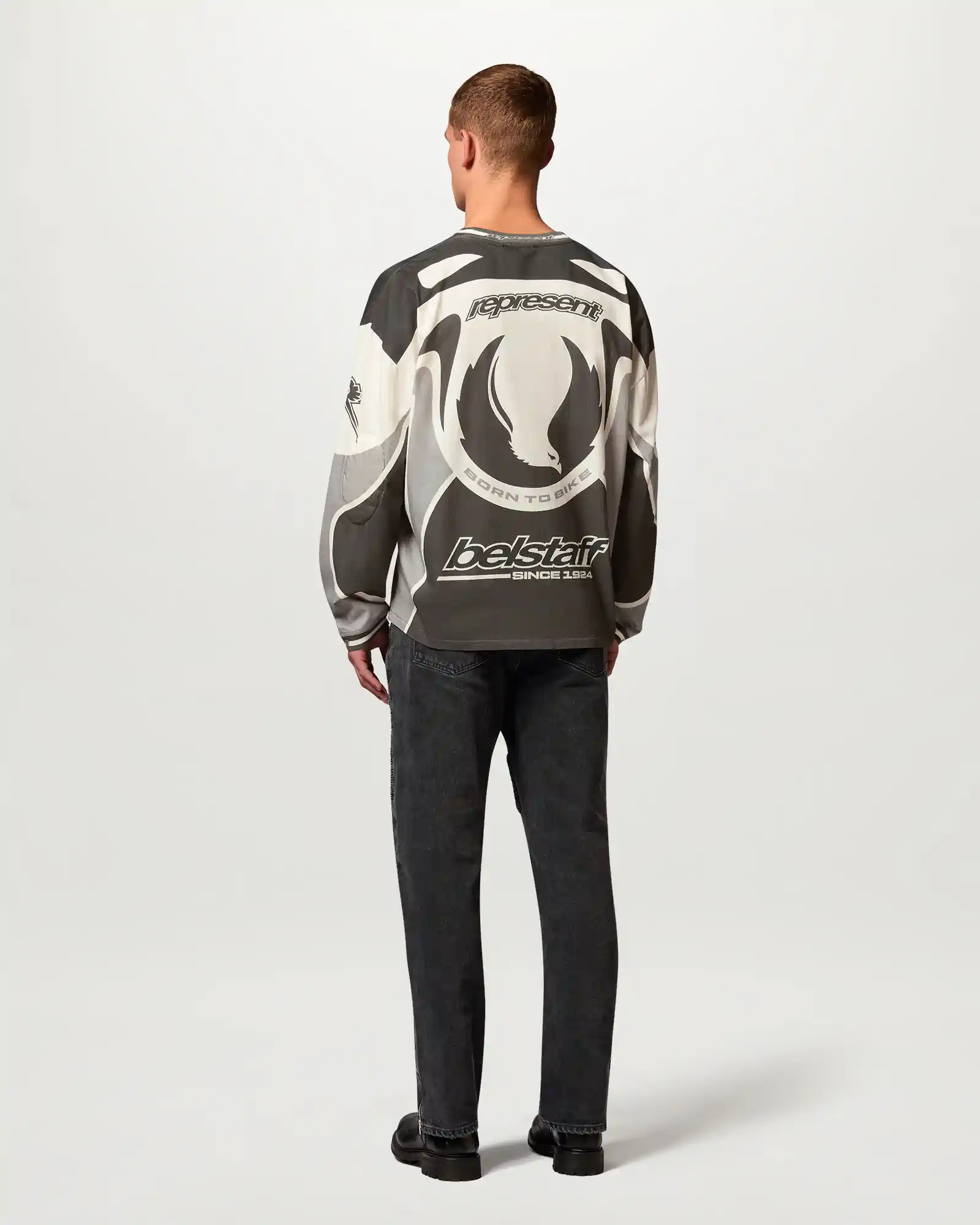 Man facing away wearing a black and white Belstaff graphic long-sleeve shirt with logos and text on back.