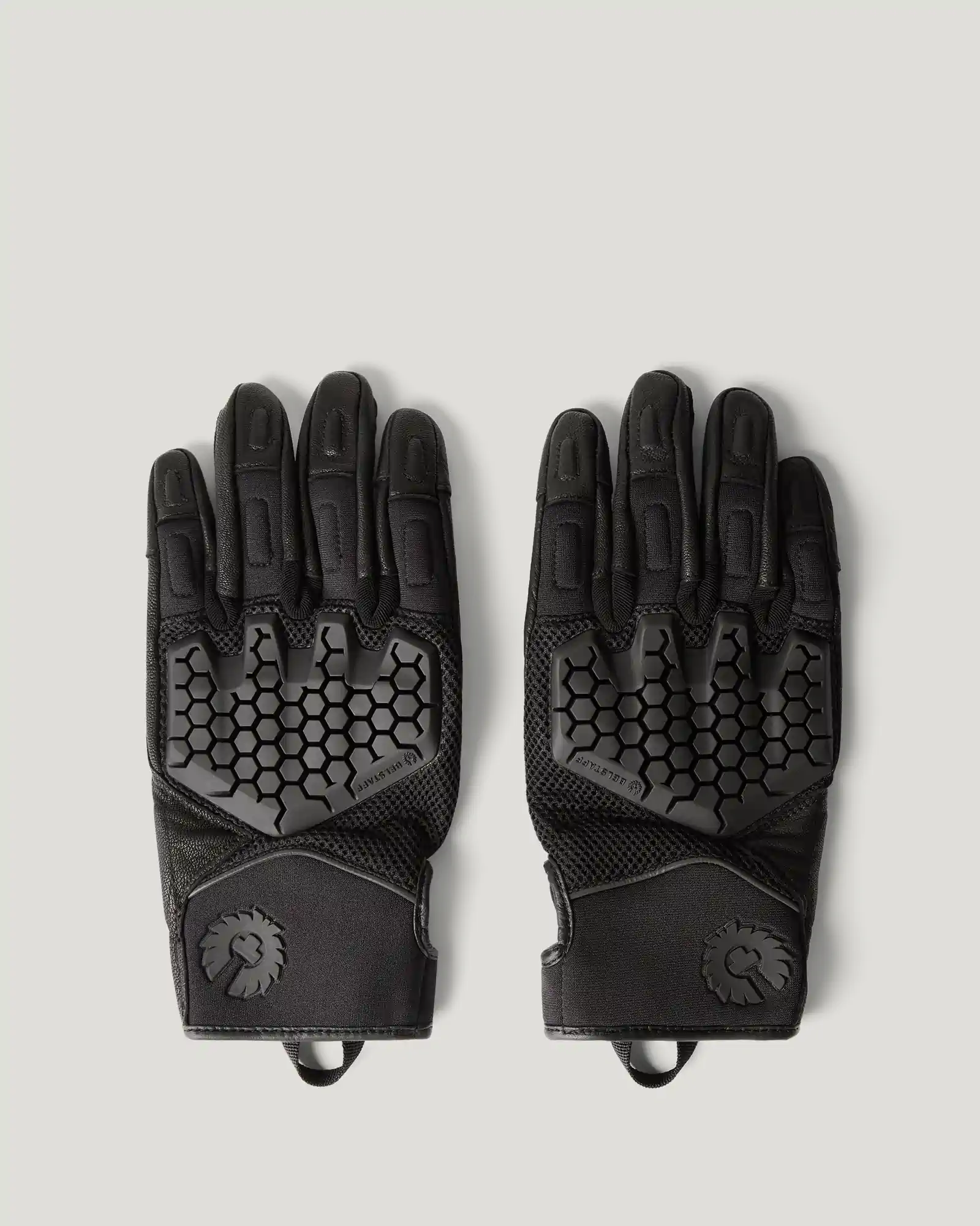 Pair of black Belstaff protective gloves with hexagonal knuckle padding and wrist logo, laid flat on gray background.