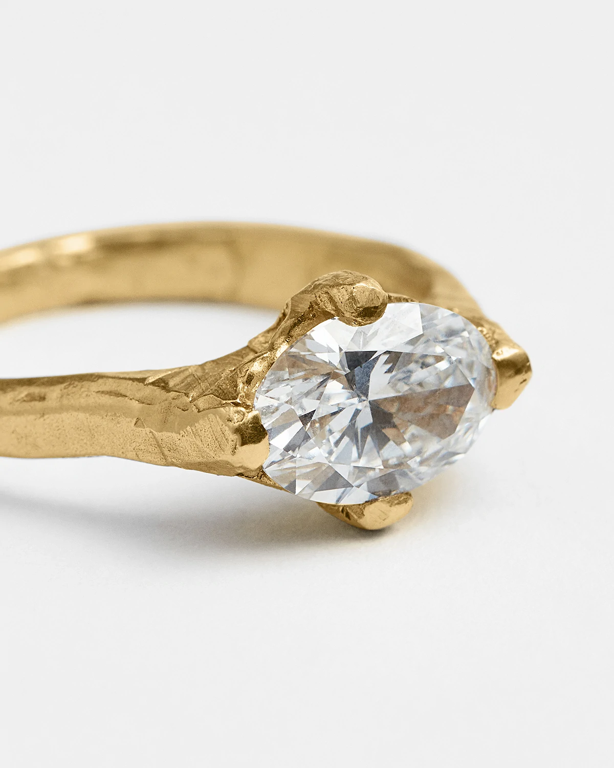 Close-up of gold ring with a large oval-cut clear gemstone in a claw setting.