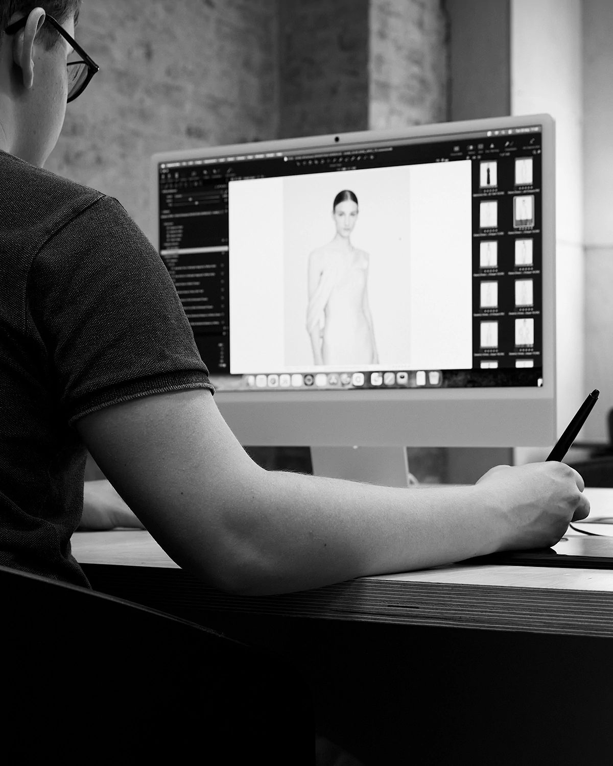Person using a digital pen to edit a on-model fashion photo of a model on a desktop computer.