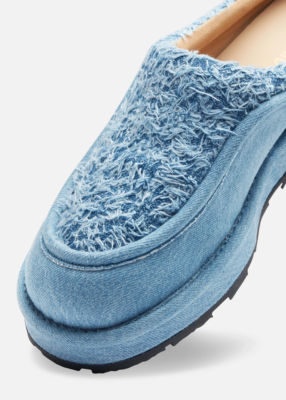 Close-up of a textured light blue Axel Arigato denim shoe with frayed fabric on top and a black sole.