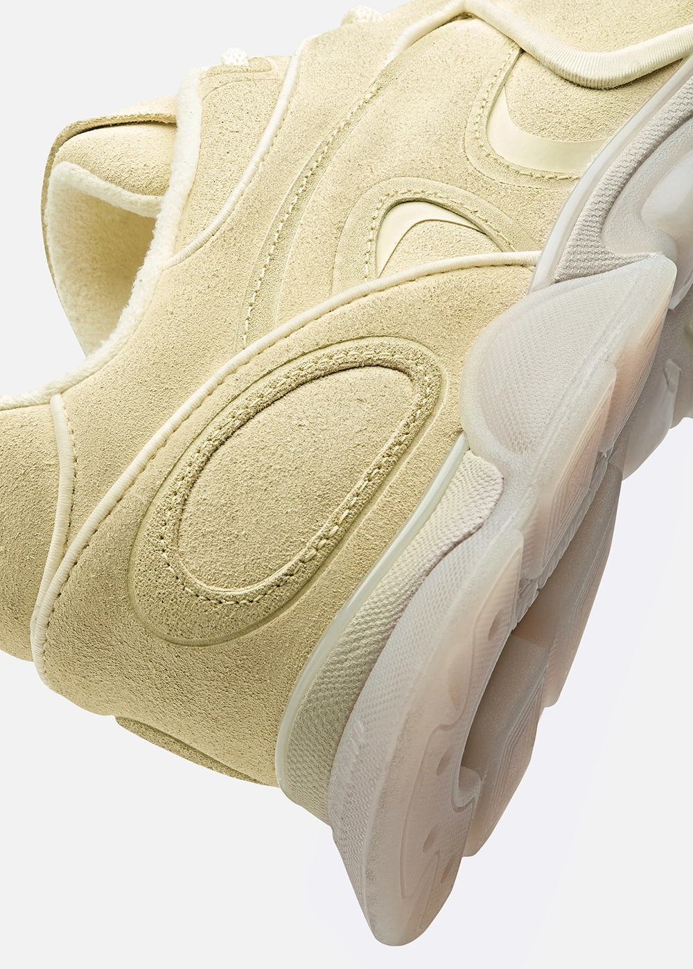 Close-up of a beige Axel Arigato suede sneaker with textured rubber sole and stitched details.