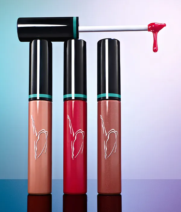 Three lip gloss tubes in nude, red, and brown shades with applicator showing red gloss drop.