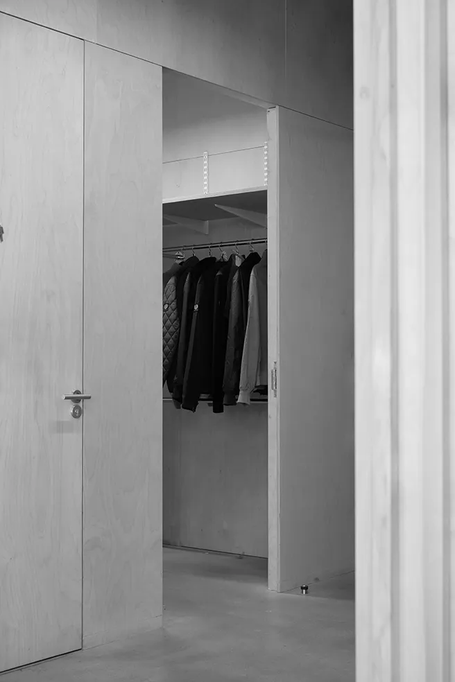 Black and white image of an open plywood wardrobe storing hanging jackets at LRP studios, used for styling during eCommerce photography.
