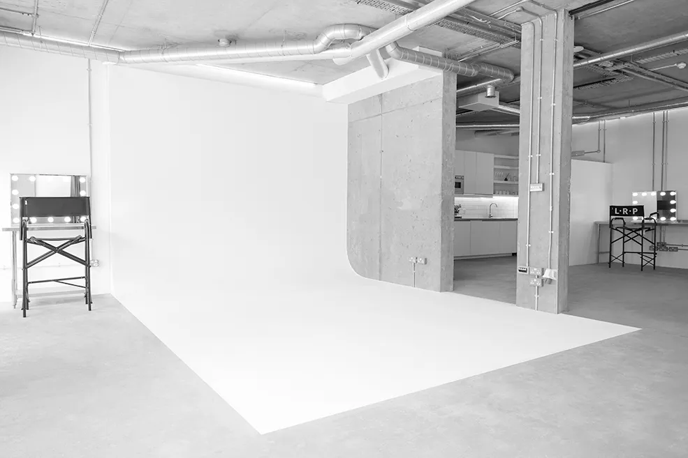 Black and white image of a large white infinity cove at LRP studios, flanked by styling stations and an industrial kitchenette, equipped for eCommerce photography.