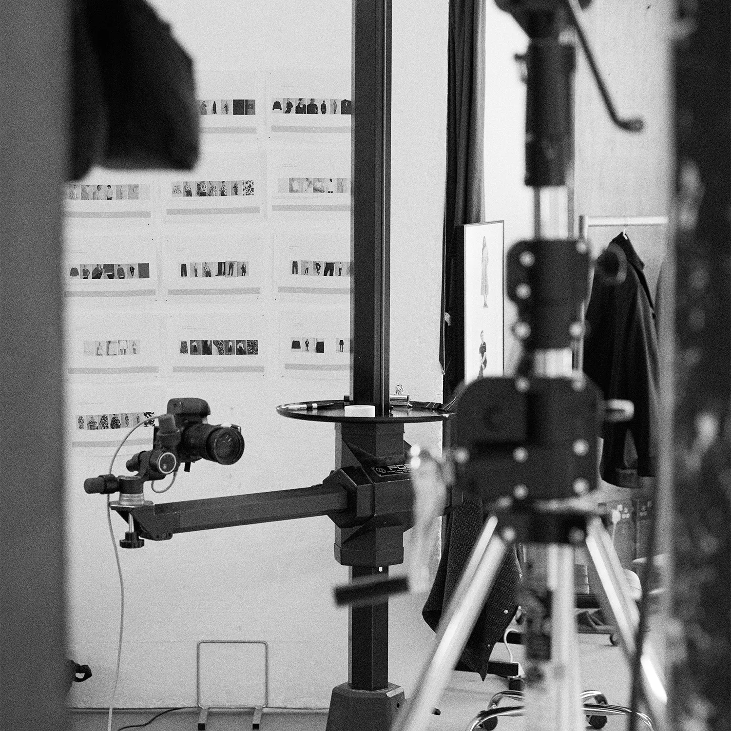 Black and white image of a professional camera mounted on a heavy studio stand at LRP studios, with a detailed printed shot list on the wall behind it, prepared for eCommerce photography.