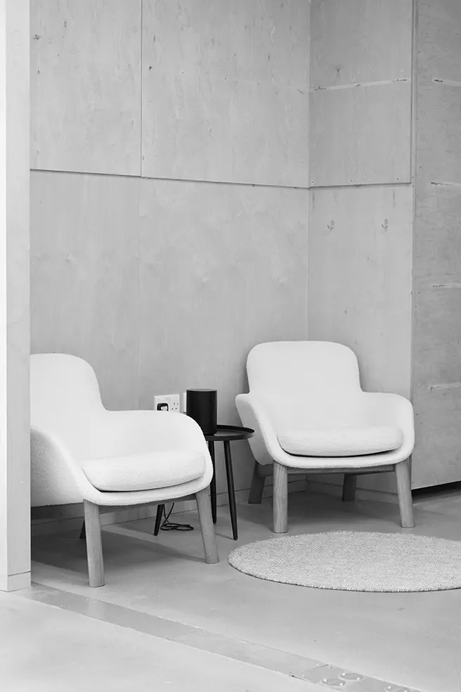 Black and white image of a minimalist lounge area at LRP studios, featuring two modern armchairs and a small side table, providing a relaxation space during eCommerce photography shoots.