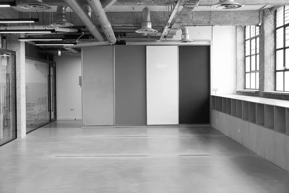 Black and white image of a spacious, open-plan industrial area at LRP studios, featuring sliding partitions and large windows, suitable for flexible eCommerce photography setups.