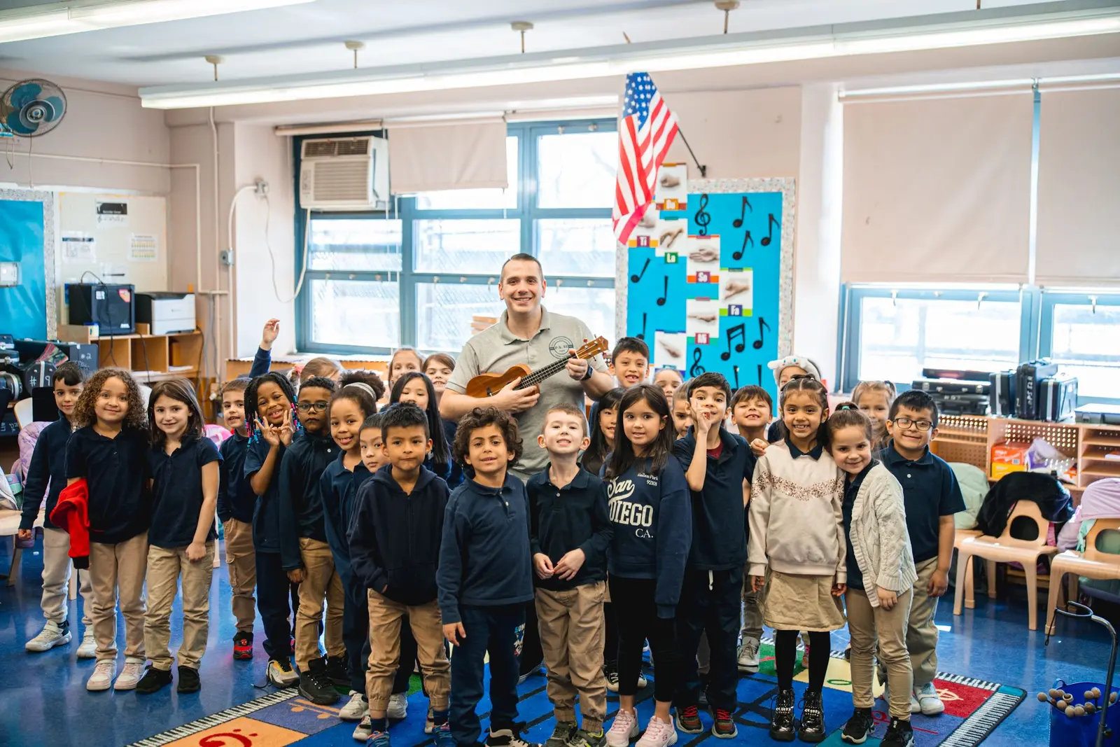 Teacher playing ukulele with smiling elementary students in classroom