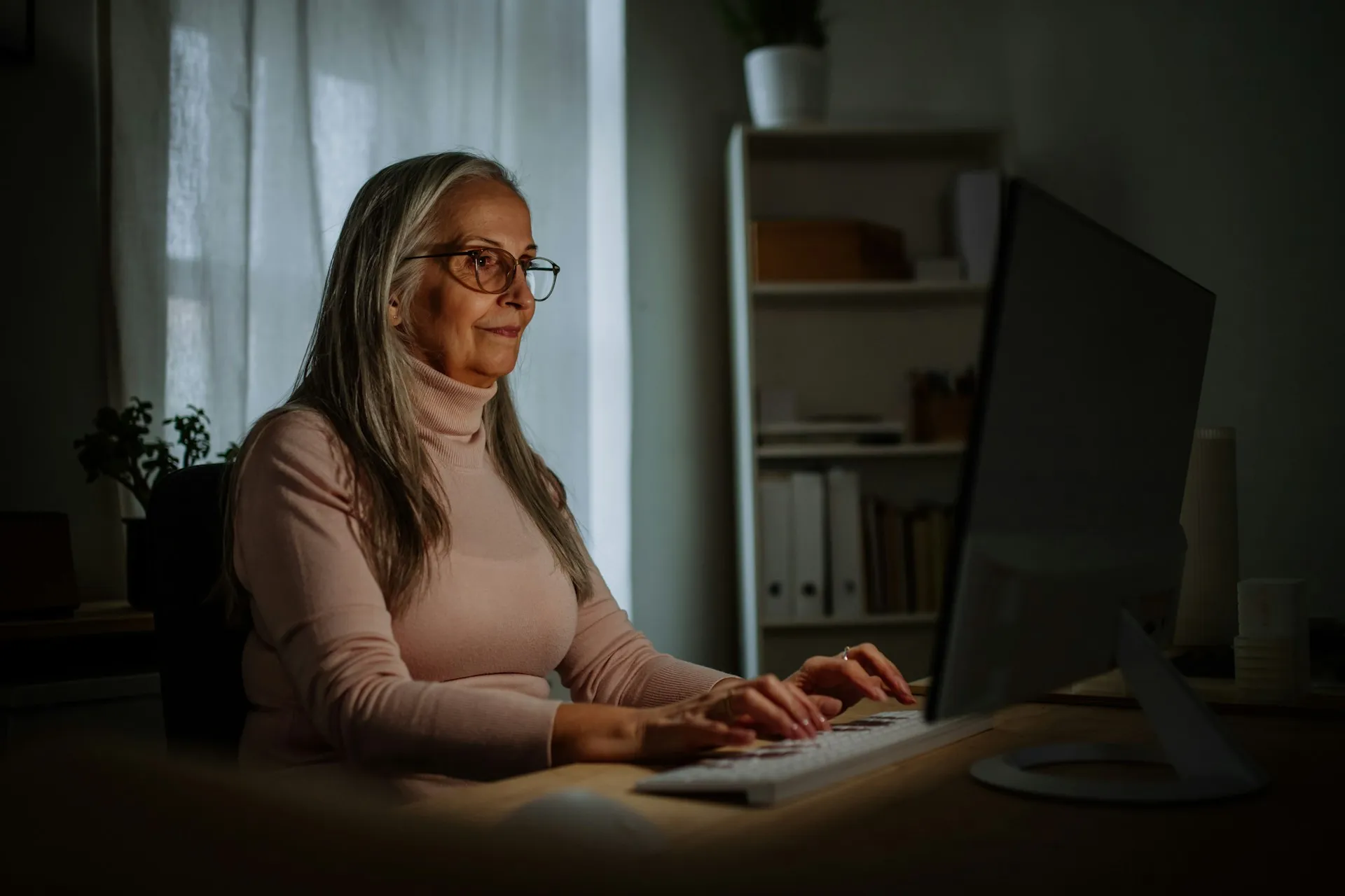 A woman focused at her computer in a bright workspace, representing the goal-driven clients Sears Group partners with.