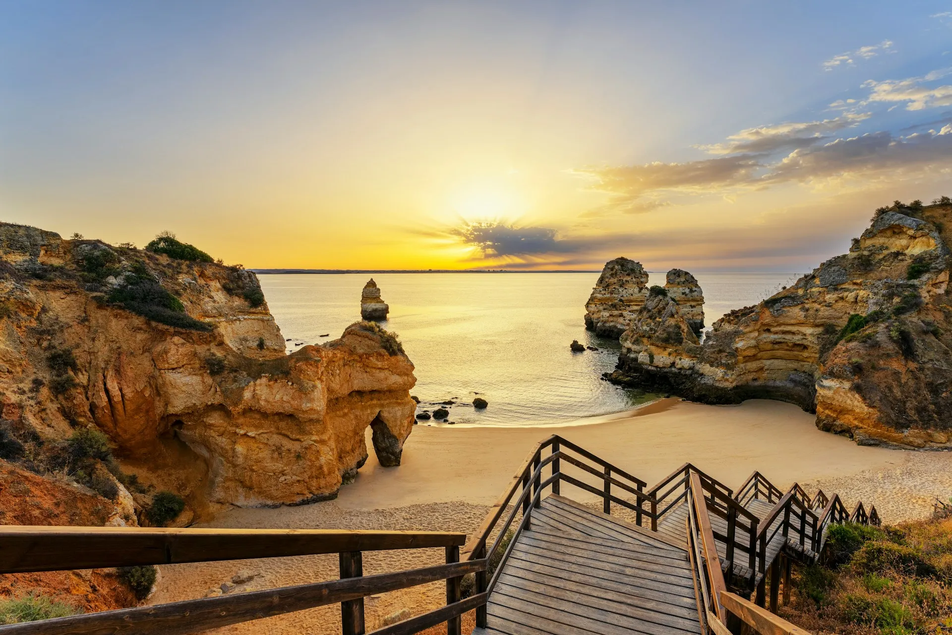 A wooden staircase leading down to a sandy beach, representing the journey toward a fulfilling retirement.