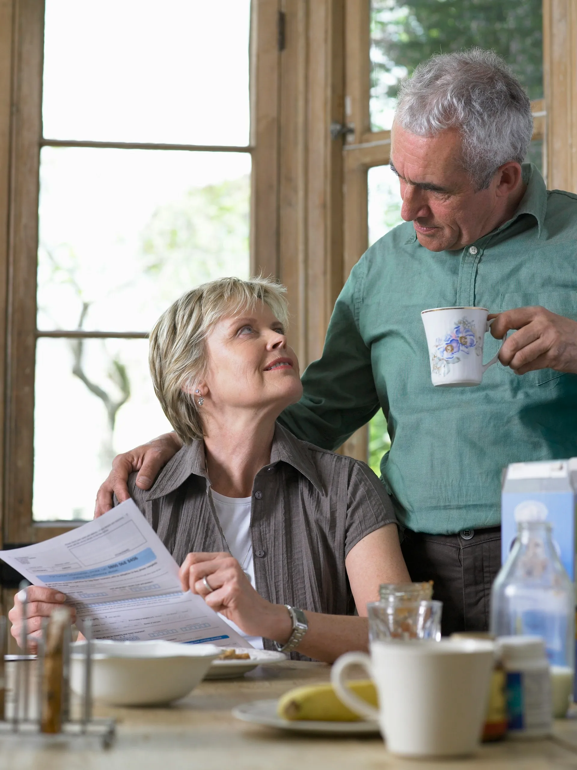 A husband and wife reviewing financial documents together at home, taking an active role in their financial planning.